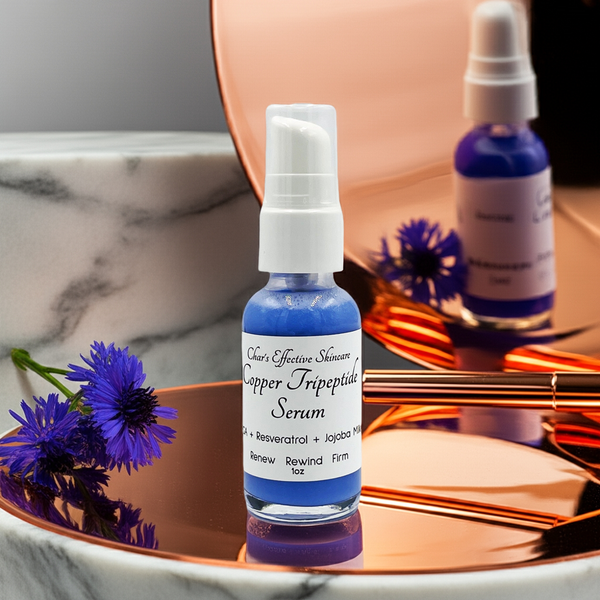 Creative photo of Copper Serum with clear bottle and white top on a copper platform reflected in a copper mirror with cornflowers